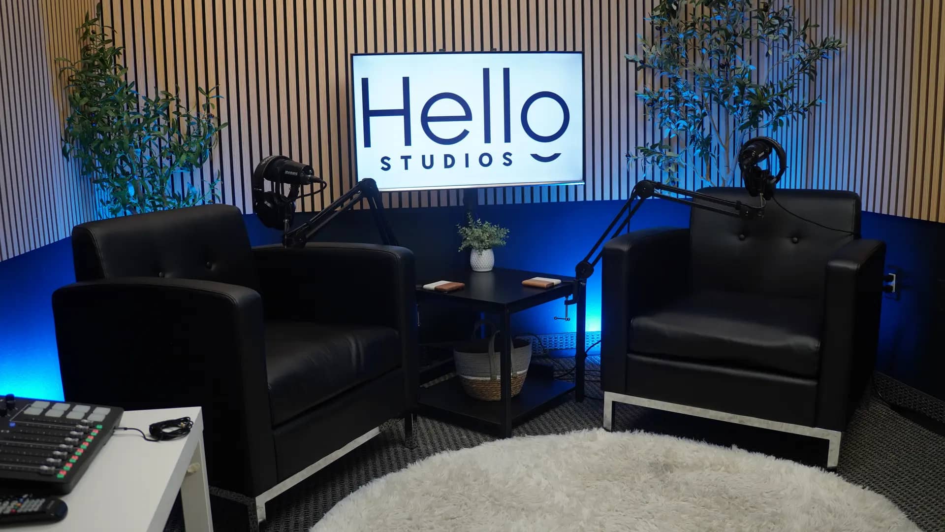The Onyx lounge set: two black leather club chairs, a backlit Hello Studios sign, wood-slat walls, and blue accent light.