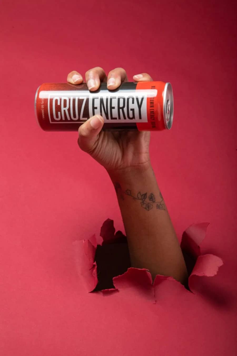 Commercial product photography, Cruz Energy A hand bursting through red paper holding a Cruz Energy drink can, a commercial product shot produced by Sierra Media Productions.